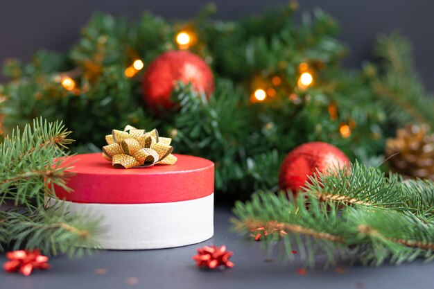 Caixa de presente vermelha redonda com fita dourada e bolas. surpresa, presente na decoração de natal.