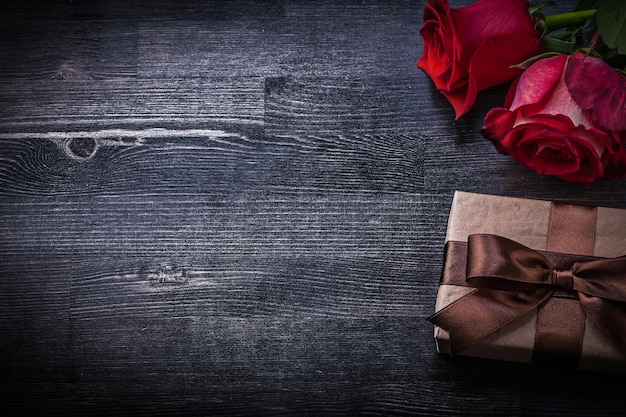 Caixa de presentes de rosas vermelhas florescidas no conceito de férias de fundo de madeira