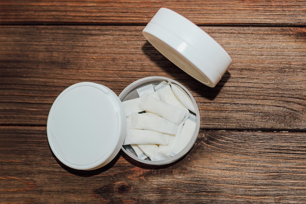 Caixa de snus com bolsas de nicotina em fundo de madeira