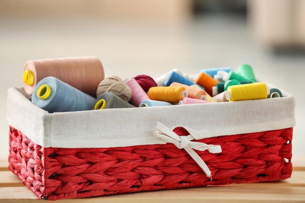 Caixa de vime com linhas de costura coloridas e ganchos de crochê na mesa