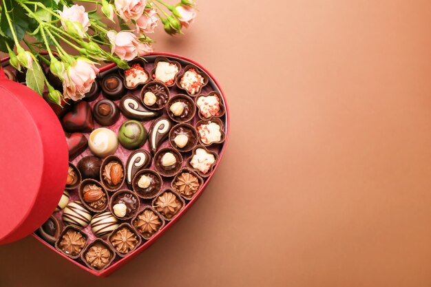 Caixa em forma de coração com bombons de chocolate e flores coloridas