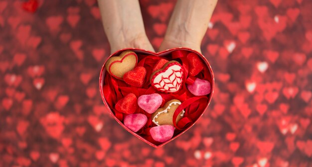 Caixa em forma de coração, com jujubas em forma de coração, biscoitos em forma de coração e fundo vermelho