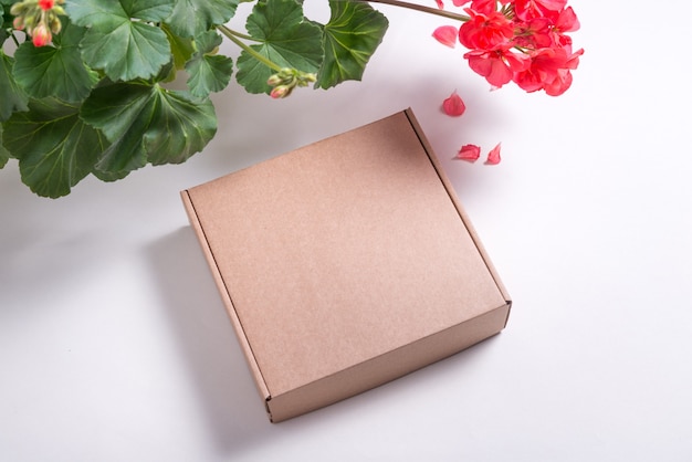Caixa lisa de papelão marrom sobre fundo branco decorada com flores frescas