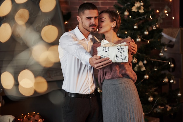 Caixa na mão alongada. presente de natal para a mulher. cavalheiro de terno clássico dá a sua esposa o presente