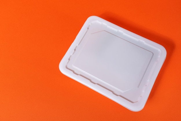 Caixa plástica branca de fast food em fundo laranja - vista lateral, isolar