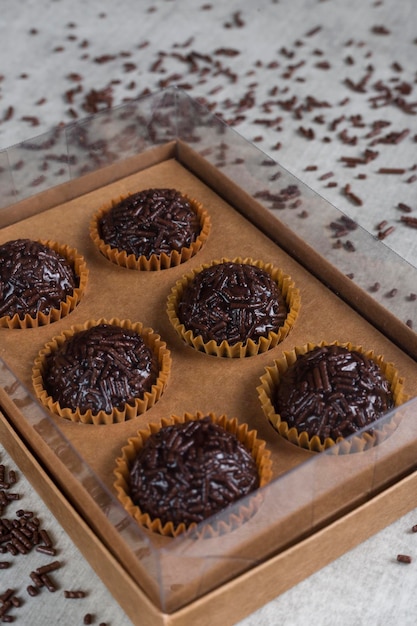 Caixa transparente cheia de brigadeiro doce brasileiro em uma mesa de madeira Versão vegana