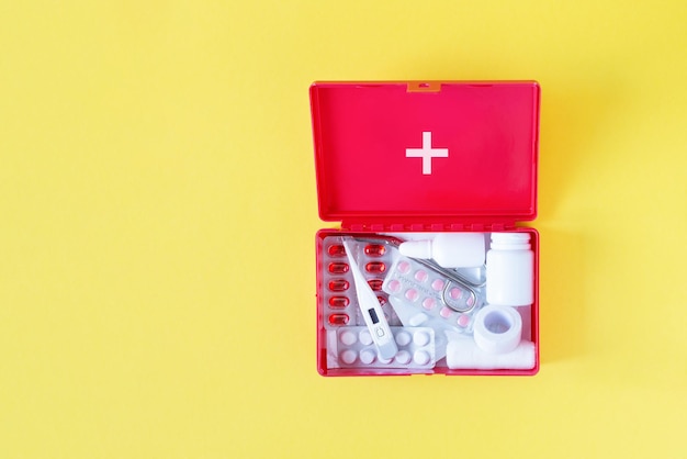 Caixa vermelha do kit de primeiros socorros com equipamentos médicos e medicamentos para vista superior de emergência
