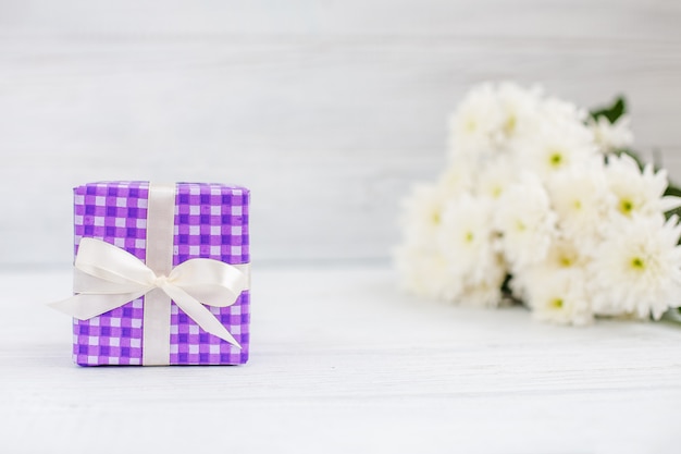 Caixa violeta com um presente e flores. O conceito do dia das mães, aniversário, 8 de março.