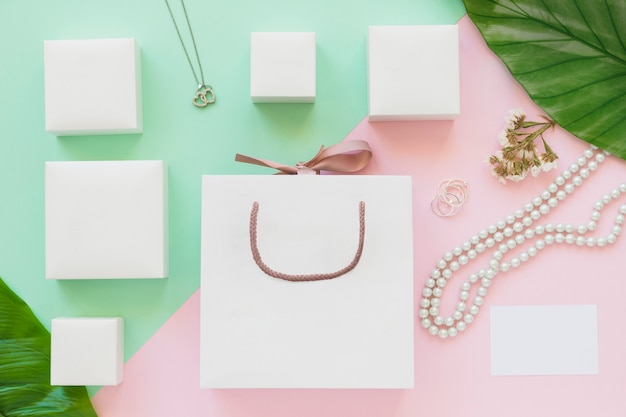 Caixas de jóia branca e sacola de compras em fundo de papel colorido