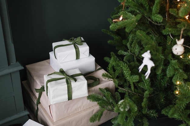 Caixas de natal com presentes amarrados com fitas sob uma árvore com luzes