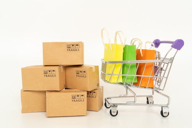 Foto caixas de papel e um carrinho no fundo branco. conceito on-line de compras ou comércio eletrônico e conceito de serviço de entrega com espaço de cópia