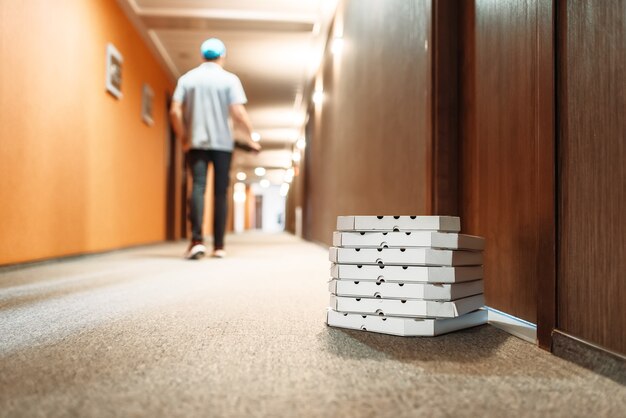 Caixas de papelão com pizza na porta do cliente, entregador vai embora