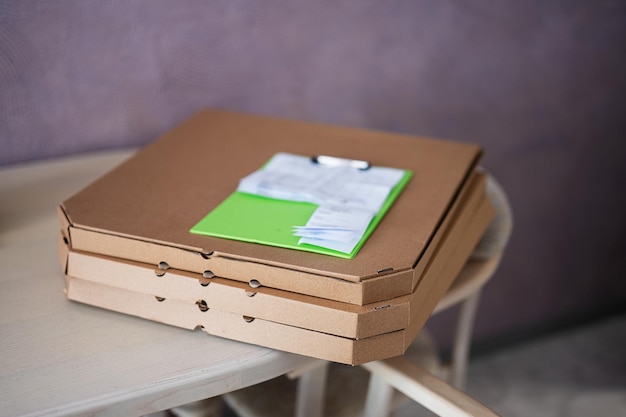 Caixas de pizza de papelão com prancheta de entrega na cozinha na mesa