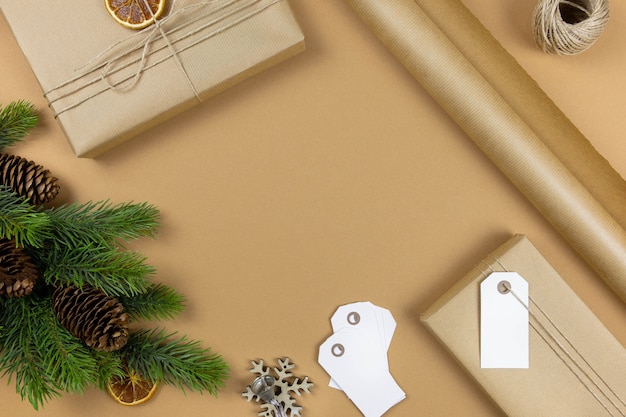 Caixas de presente artesanal de Natal com maquete de etiqueta de etiqueta, pinhas, galhos de árvores de abeto e decoração em fundo de papel ofício. Composição com estilo festivo. Vista do topo. Copie o espaço.