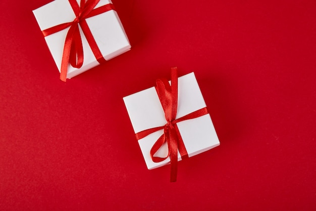 Caixas de presente branca de luxo com fita vermelha em fundo vermelho.