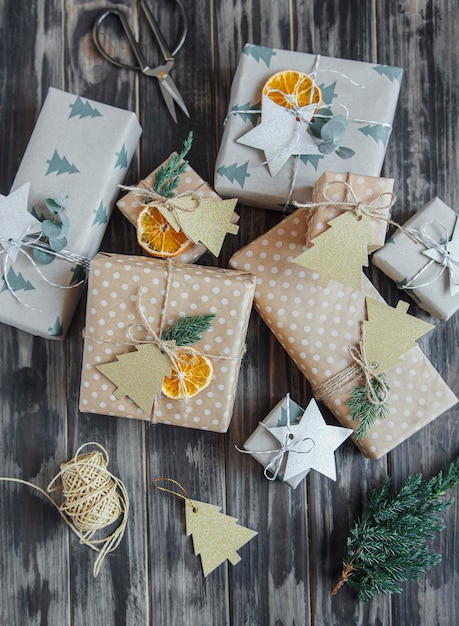 Caixas de presente caseiras decorativas de natal embrulhadas em papel kraft marrom em um fundo de madeira cinza escuro