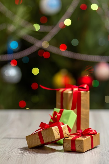 Caixas de presente com arcos vermelhos e árvore de Natal turva com luzes de festa cintilantes e bolas de brinquedo