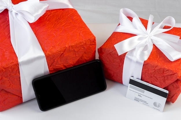 Caixas de presente com cartão de crédito e smartphone em cima da mesa. Pagamento online. Conceito de comércio e internet banking