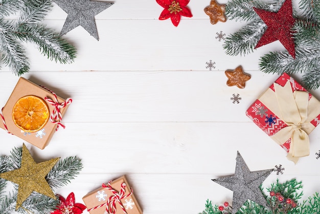 Caixas de presente com decoração de ramos e brinquedos de abeto vermelho de neve em um fundo branco de madeira. Cartão de Natal. Copos leigos plana