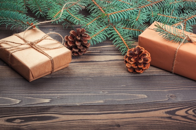 Caixas de presente de natal e galho de árvore do abeto na mesa de madeira