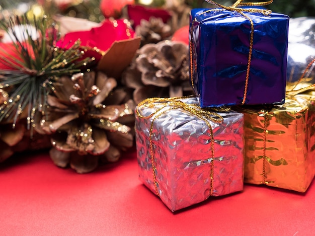Caixas de presente de natal embrulhadas em cores diferentes sob a árvore de natal em fundo vermelho. . decoração festiva de interiores.