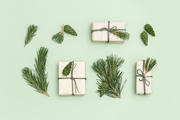 Caixas de presente de Natal embrulhadas em papel reciclado leve, decoradas com ramos de pinheiro e pinho verde