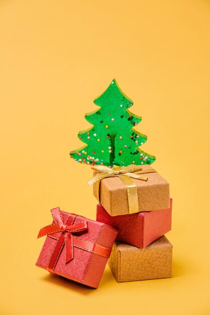 Caixas de presente e uma árvore de natal em um fundo amarelo com espaço de cópia.