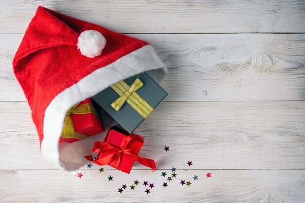 Caixas de presente em um chapéu de Papai Noel em um fundo de madeira