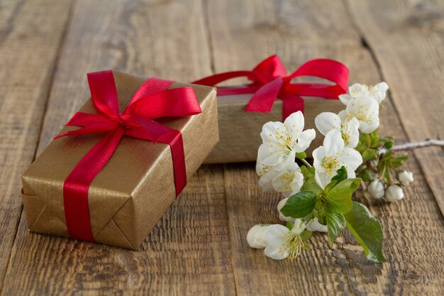 Caixas de presente embrulhadas com fitas vermelhas decoradas com flores de jasmim em placas de madeira. O tom da cor mudou.