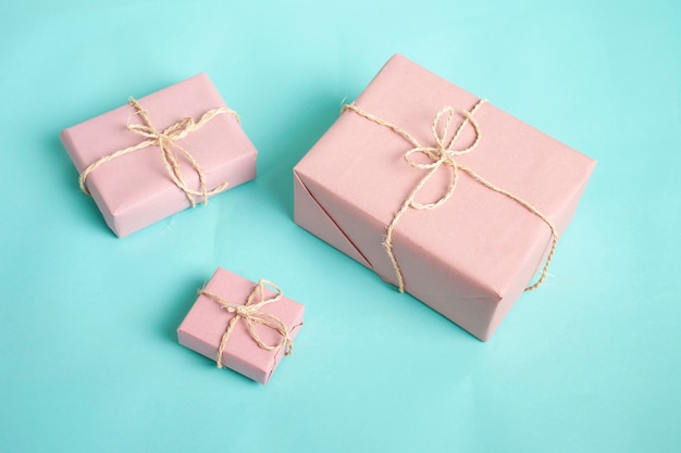 caixas de presente embrulhadas em papel rosa e amarradas com barbante em um fundo azul. Conceito de Natal