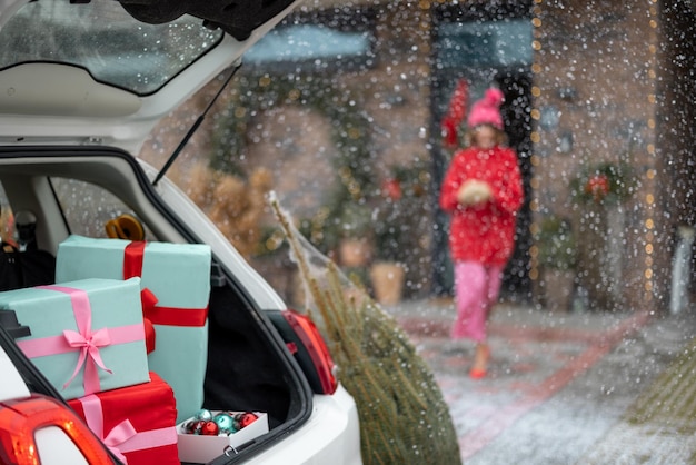 Foto caixas de presente no porta-malas do veículo em frente a uma casa decorada para férias de inverno