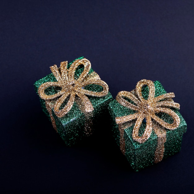 Caixas de presente verdes de decoração de natal com laço de ouro brilhante em fundo quadrado escuro