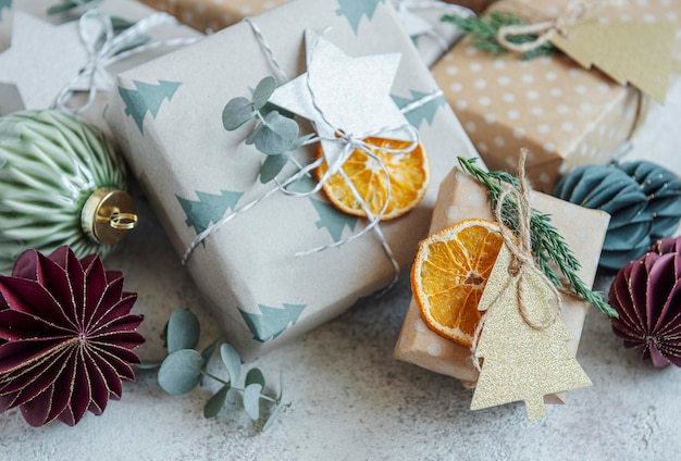 Caixas de presentes caseiras decorativas de Natal embrulhadas em papel kraft marrom sobre um fundo cinza de concreto