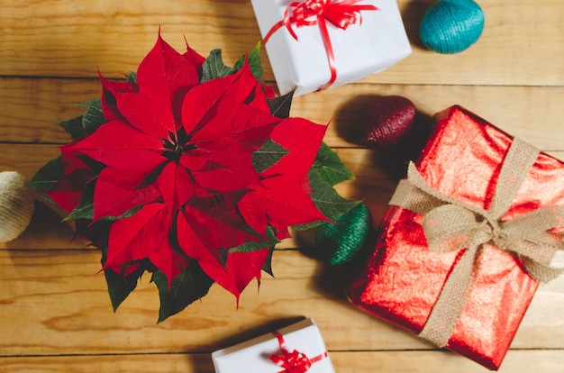 Caixas de presentes e poinsettias em mesa de madeira