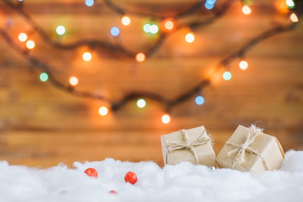 Foto caixas de presentes na neve decorativa perto de luzes de fadas