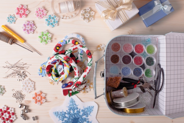 Caja de abalorios con abalorios de colores y herramientas para realizar bisutería. Preparación para artesanías