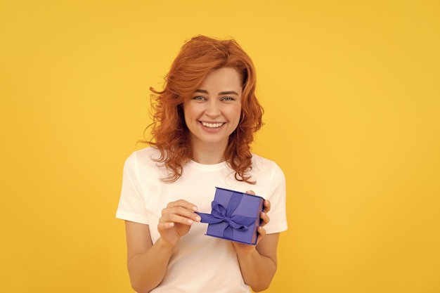 Caja abierta de niña positiva sobre fondo amarillo regalo del día del boxeo y compra de regalos