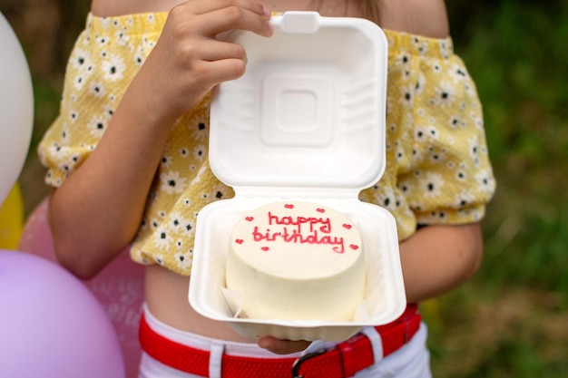 Una caja abierta con un pastel bento para un cumpleaños en manos de una persona