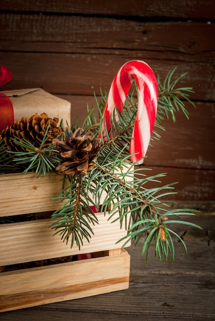 Foto caja con adornos navideños, ramas de árboles de navidad y regalos.