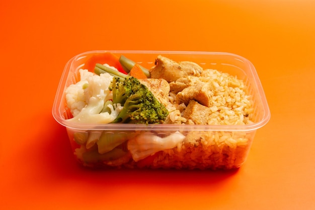 Caja de almuerzo envasada saludable comida preparada en casa en un fondo naranja limpio vista delantera