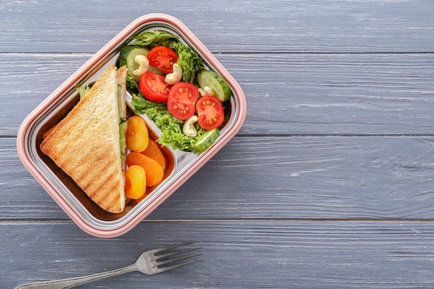 Caja de almuerzo escolar con comida sabrosa en madera