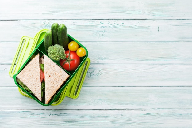 Caja de almuerzo con verduras y sándwich