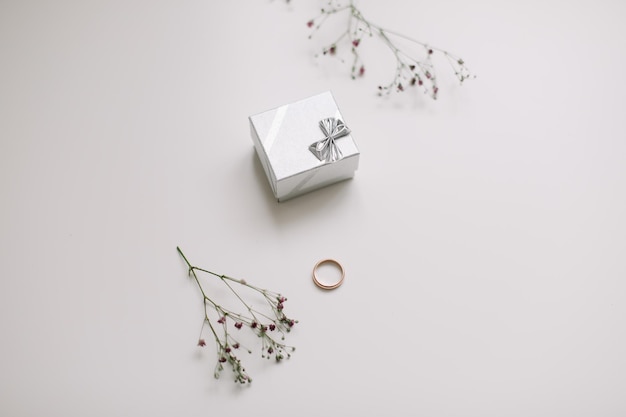 Caja con anillo de compromiso dorado sobre fondo de flores vista superior Concepto de propuesta de matrimonio de boda