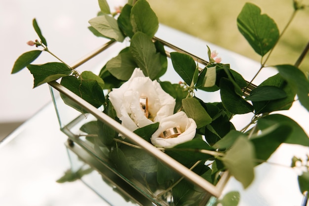 Una caja con anillos de boda y flores.