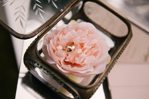 Una caja con anillos de boda y flores.