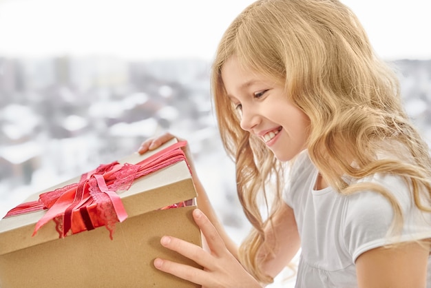 Caja de apertura de niña sonriente con lazo rojo.