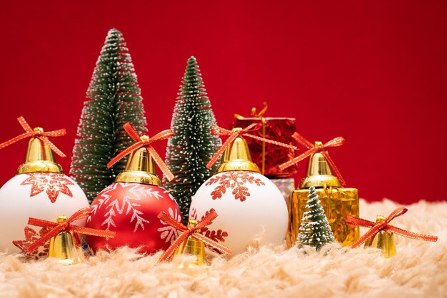 Caja y árbol de regalo de la Navidad con las campanas de oro, conos del pino en fondo rojo