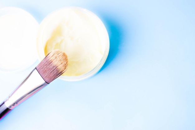 Una caja de belleza con un cepillo de madera hecho de pelusa dura natural para un tono y un bote redondo de crema.