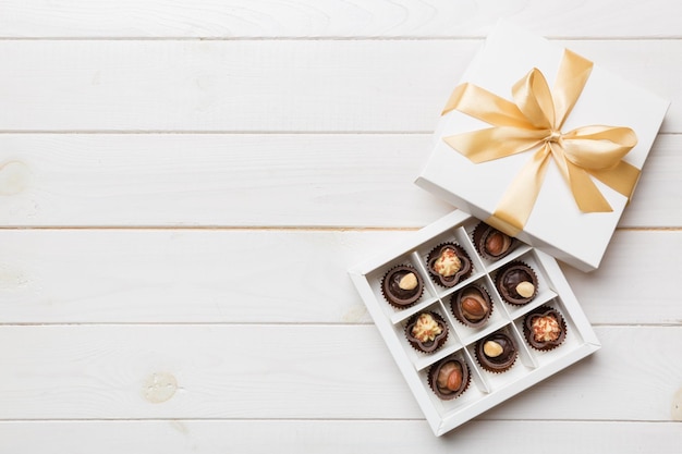 Caja blanca con dulces de chocolate y vista superior de cinta dorada con espacio de copia