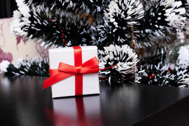 Caja blanca con regalo y árbol de navidad.